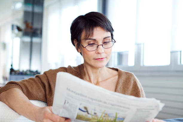 Femme presbyte qui lit son journal avec des lunettes de lecture