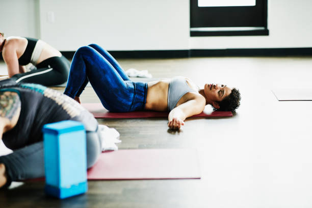 Femme couchée sur le dos, sur un tapis de sport dans une salle fitness