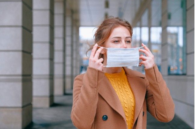 Jeune femme qui enfile un masque pour faire barrière contre les microbes